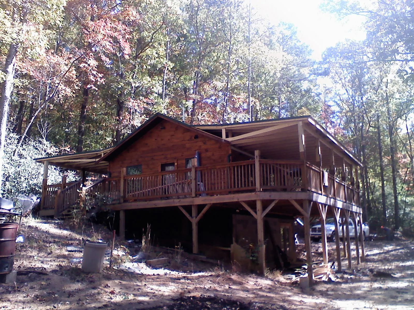 Log cabin with a wraparound porch and metal roof in the fall in Grafton